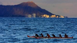 Des hommes rament leur canoe en direction de la plage de Waikiki à Honolulu (Hawaï). (Illustration)