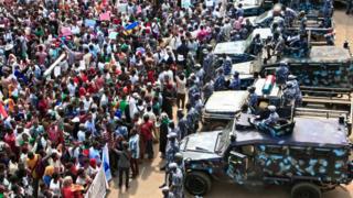 People rally before security forces' vehicles at a mass demonstration near the presidential palace in Sudan's capital Khartoum