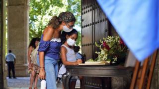 Cuban Kresla Brutau (C) and her daughter Maria Carla write in the condolence book for the late Eusebio Leal on August 1, 2020 in Havana, Cuba.