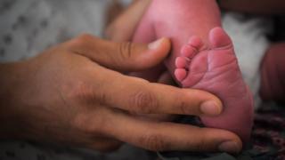 This file photo shows a mother holding the foot of her newborn baby in hospital in Nantes, France - faces of mother and child are out of frame