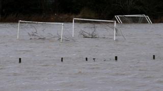 Tree debris is washed away on flooded football pitches in Tadcaster, northern England.