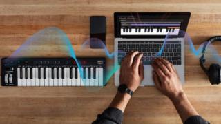 Amazon's music keyboard on a desk next to a laptop and headphones