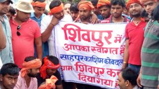बैनर के साथ खड़े ग्रामीण