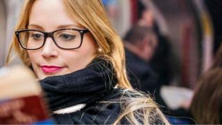 شابة تقرأ وهي تجلس في إحدى وسائل المواصلات