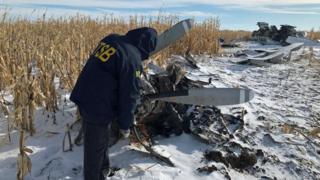 An investigator looks at wreckage of plane in the snow
