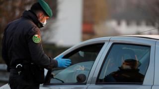 Член Guardia di Finanza в маске останавливает машину во время вспышки коронавируса на севере Италии