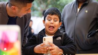 A boy pulls a face at a mobile phone