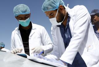 Medical staff take notes as they check people's temperature on the street as a precautionary measure against the spread of coronavirus in Yemen.