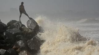 Ein Mann auf einem Felsen an der Küste bei Flut in Versova