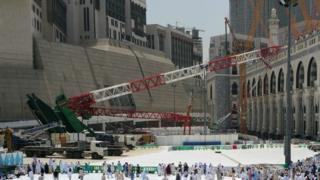 Muslim pilgrims walk past the crane that collapsed at the Grand Mosque in Saudi Arabia's holy Muslim city of Mecca - 12 September 2015