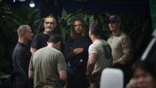   A group of foreign divers and US soldiers, dressed in light-colored shirts, gather in Tham Luang cave while the 12 boys and their trainer are trapped in the cave of Khun Nam Nang Park in Mae Sai. District of Chiang Rai Province on July 6, 2018 