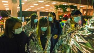 Injured protesters wrapped in emergency thermal blankets leave the campus of the Hong Kong Polytechnic University