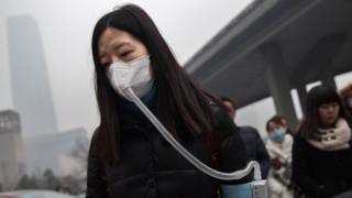 Китайская женщина носит маску и фильтр, когда идет на работу во время сильного загрязнения 9 декабря 2015 года в Пекине, Китай