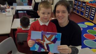 Mother and son at school holding a piece of artwork