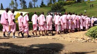 Abaregwa bakabakaba 60 binjiye mu rukiko bambaye imyenda y'iroza, babiri baziritse mu ipingu rimwe