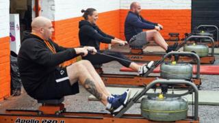 People using rowing machines outside a gym