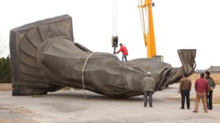 This photo taken on April 7, 2018 shows workers lifting a toppled status of China's first emperor "Qin Shi Huang" in Binzhou in China's eastern Shandong province.