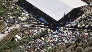 Hundreds of characters are scattered around the building in an aerial view of the Jonestown site