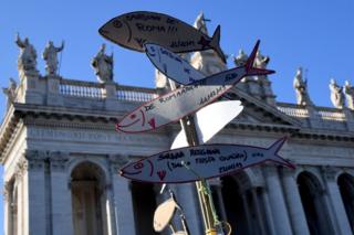 A demonstrator holds cardboard cutouts of sardines during a "Sardine Movement" rally in Rome, 14 December