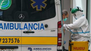 Un agent de santé en tenue de protection aide un homme à sortir d'une ambulance devant l'hôpital de Burgos, dans le nord de l'Espagne, le 23 mars 2020