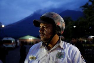 A firefighter looks on with Fuego volcano in the background