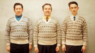 Three men pose wearing matching Fair Isle jumpers on one of the Shetland Islands in 1970
