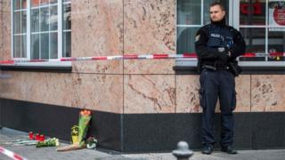 A policeman stands next to some flowers left at the scene of the shooting in Hanau
