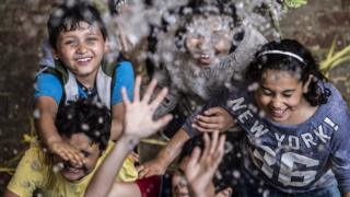 Children react to holy water being sprayed on them