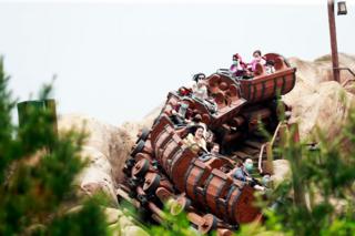 Riders wearing face masks are seen on the Seven Dwarfs Mine Train