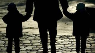 A women with two children walking on a street