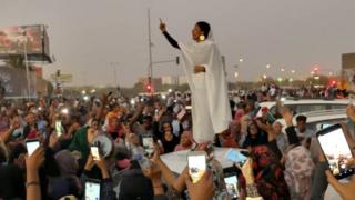 Alaa Salah, gestures (as people film her on their mobile phones) during a protest, along a bridge in Khartoum, Sudan, demanding Sudanese President Omar Al-Bashir to step down, 8 April 2019.