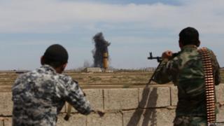 Smoke billows following an air strike as members of the Iraqi government forces hold a position on the western outskirts of Tikrit, on 27 March 2015,