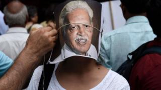 A protester adjusts a portrait of poet Varavara Rao on the face of another protester during a demonstration against the arrests of civil and democratic rights activists by the Maharashtra Police, at Parliament Street, on August 30, 2018 in New Delhi, India