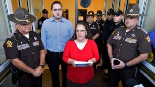 Surrounded by Rowan County Sheriff"s deputies, Rowan County Clerk Kim Davis, centre, with her son Nathan Davis standing by her side, makes a statement to the media at the front door of the Rowan County Judicial Center in Morehead, Kentucky, on Monday