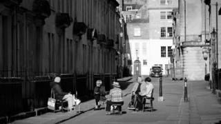 Women sit apart from each other drinking champagne in street