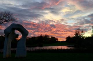Sunset over a river with by a sculpture