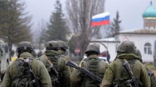 Озброєні військові в Криму на тлі російського прапора
