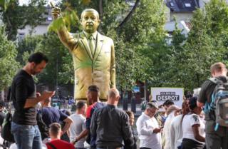 Наблюдатели смотрят на золотую статую президента Турции Реджепа Тайипа Эрдогана в городе Висбаден на площади германского единства