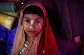   Senuara Begum, a 14-year-old Rohingya refugee, poses for a photo while she carries a thanaka paste at Jamtoli camp in Cox Bazaar, Bangladesh 