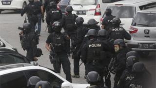 事件現場に入る重装備の警官隊(14日)