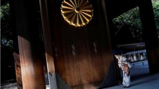 A woman wearing a kimono bows at the Yasukuni shrine in Tokyo