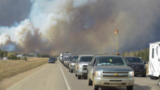 Дым наполняет воздух, когда люди едут по дороге в Форт Мак-Мюррей, Альберта, вторник, 3 мая 2016 года.