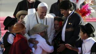 Pope Francis is surrounded by greeting children next to Bolivia's President Evo Morales after his arrival in La Paz's airport in El Alto