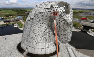 Men on crane next to Kelpies