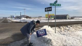A Chinese student puts up a yard sign of presidential candidate Andrew Yang in Des Moines, Iowa.
