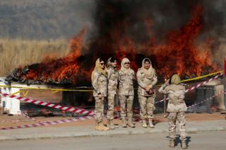 Members of the anti-narcotics force pose for a picture as drugs are burned during a ceremony in Islamabad, Pakistan