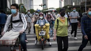 Residents wears face masks while riding their bicycles on May 11, 2020 in Wuhan, China.