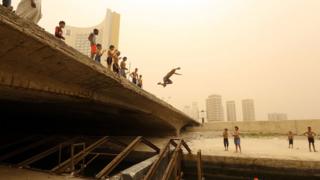 Children at a bridge, one child jumps