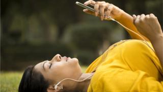Una mujer recostada en el suelo con un celular.