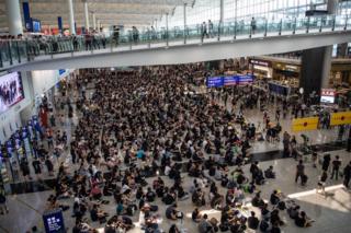 Протестующие участвуют в сидячей забастовке против насилия со стороны полиции в международном аэропорту Гонконга Чек Лап Кок
